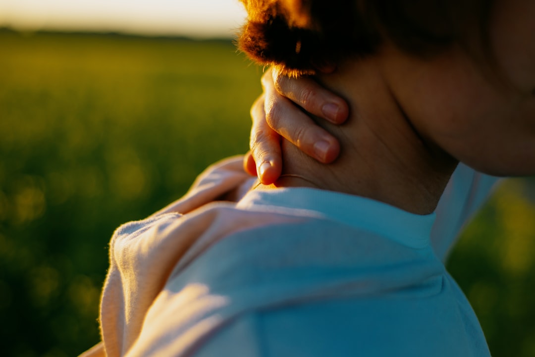 Woman in a grey t-shirt with hands on her neck