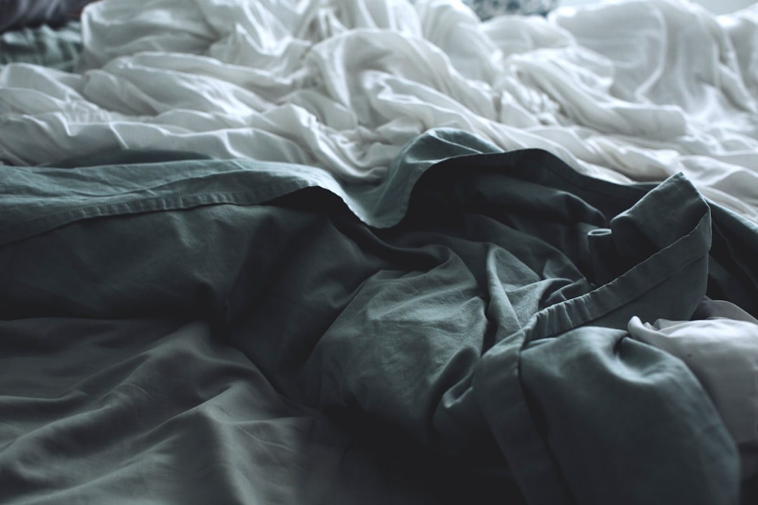 white blanket on bed near window