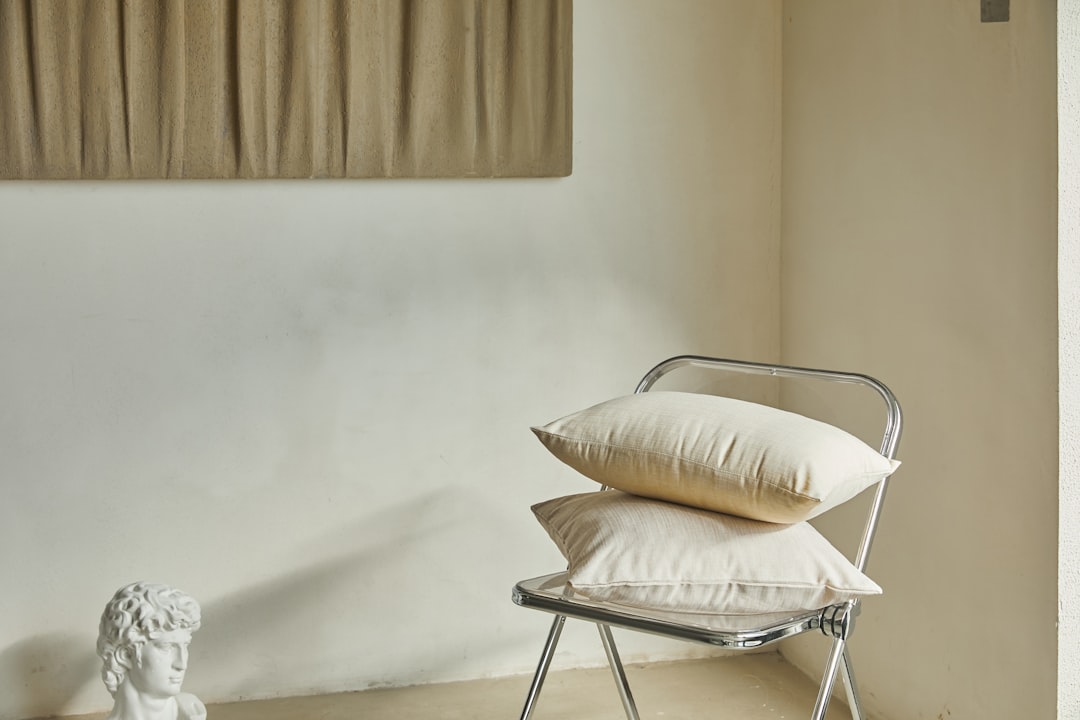 three throw pillows and one white fringed blanket placed on top of gray sofa
